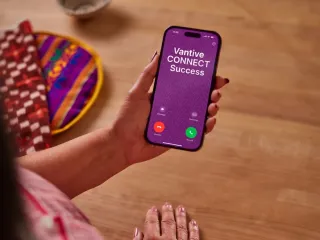 Woman looking at phone with incoming call from "Vantive CONNECT Success"