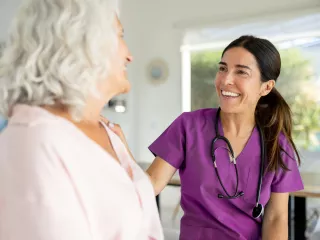 A nurse attentively converses with an elderly woman