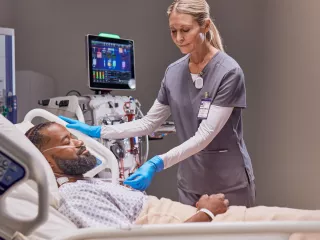 Healthcare professional with patient in hospital bed receiving treatment 