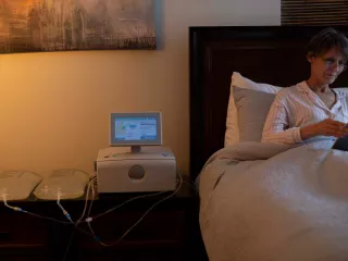 A women reads in bed with her Amia system on her nightstand
