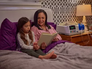 Grandmother reads to her granddaughter in her bed